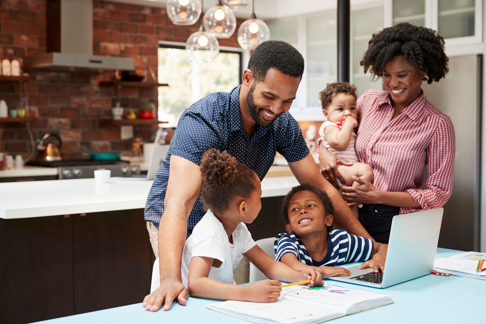 Family of five in a kitchen, children doing homework with parents watching.
