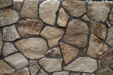 Stone wall with beige and brown rocks, dark mortar.
