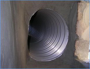 A metal corrugated pipe through a wall.