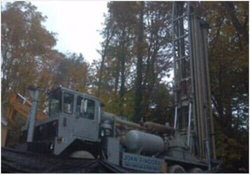 Large drilling rig truck in a wooded area at dusk