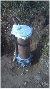 Small outdoor utility pipe with a white cap set in dirt and grass.