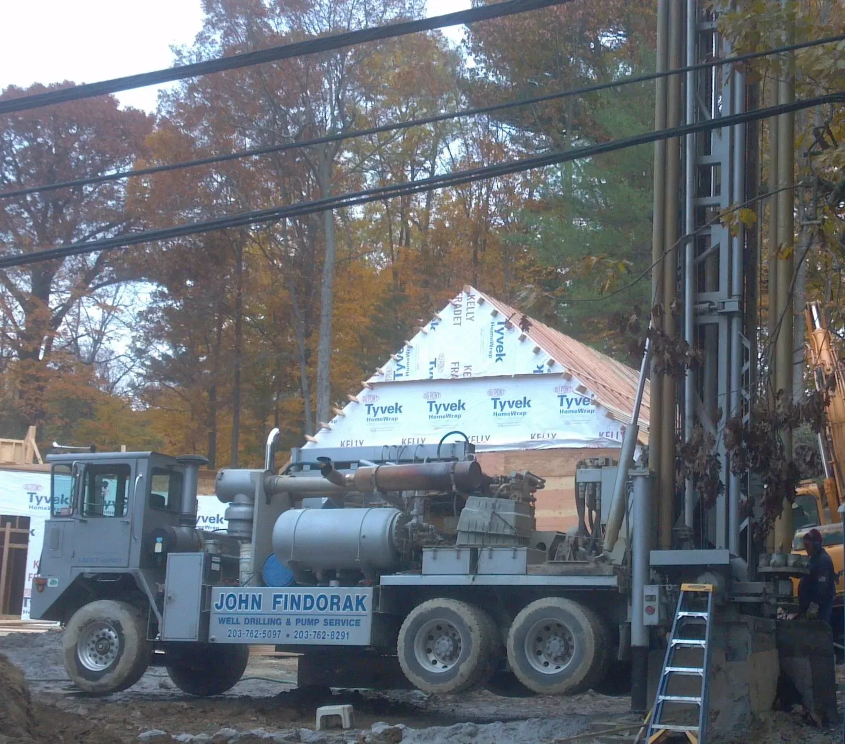 Drilling rig truck at a construction site beside a house under renovation
