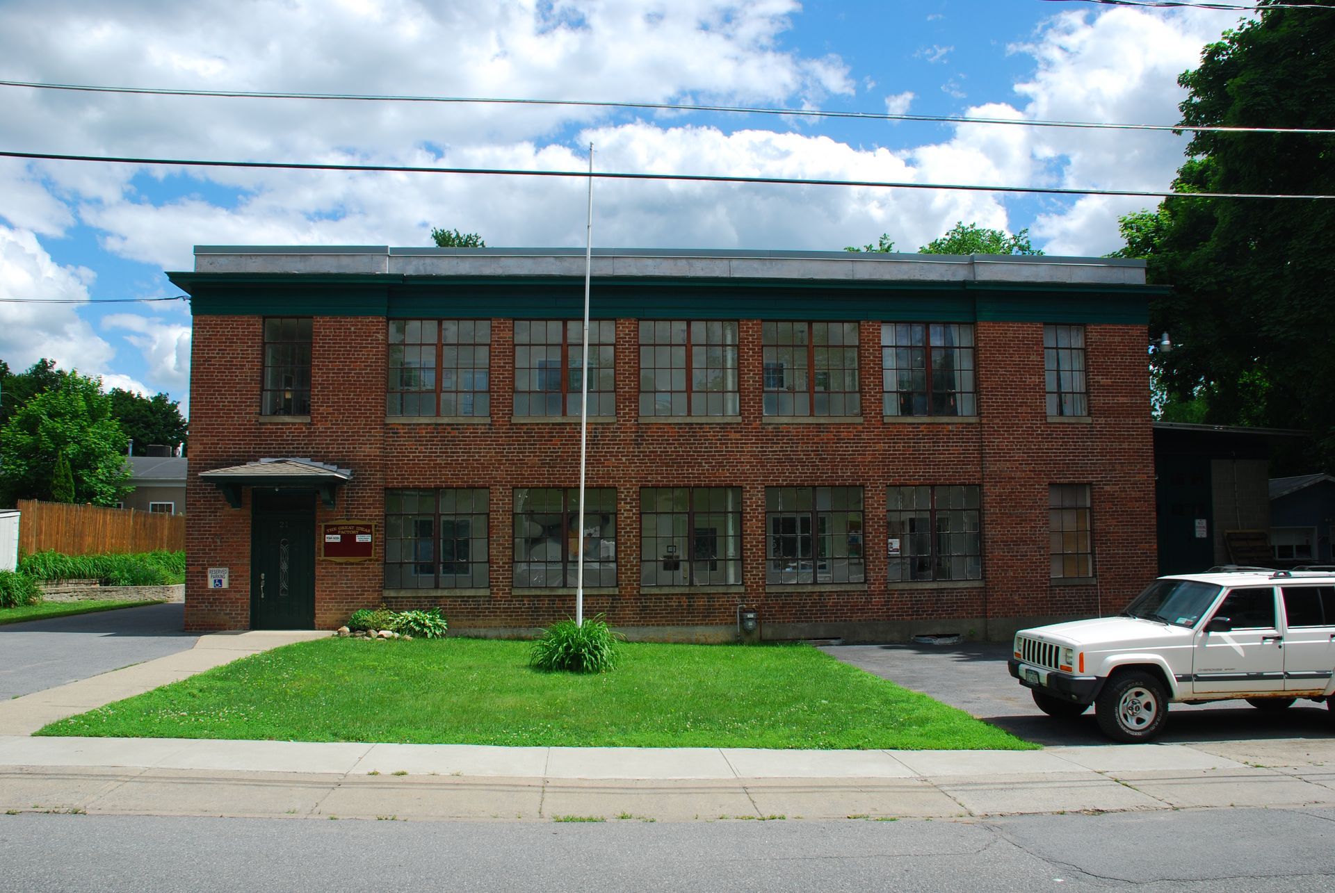 A white jeep is parked in front of a brick building