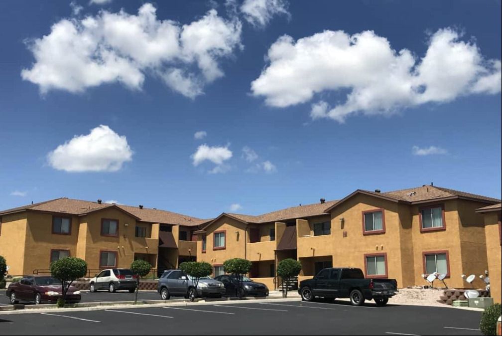 Two-story yellow apartment buildings beside a parking area.