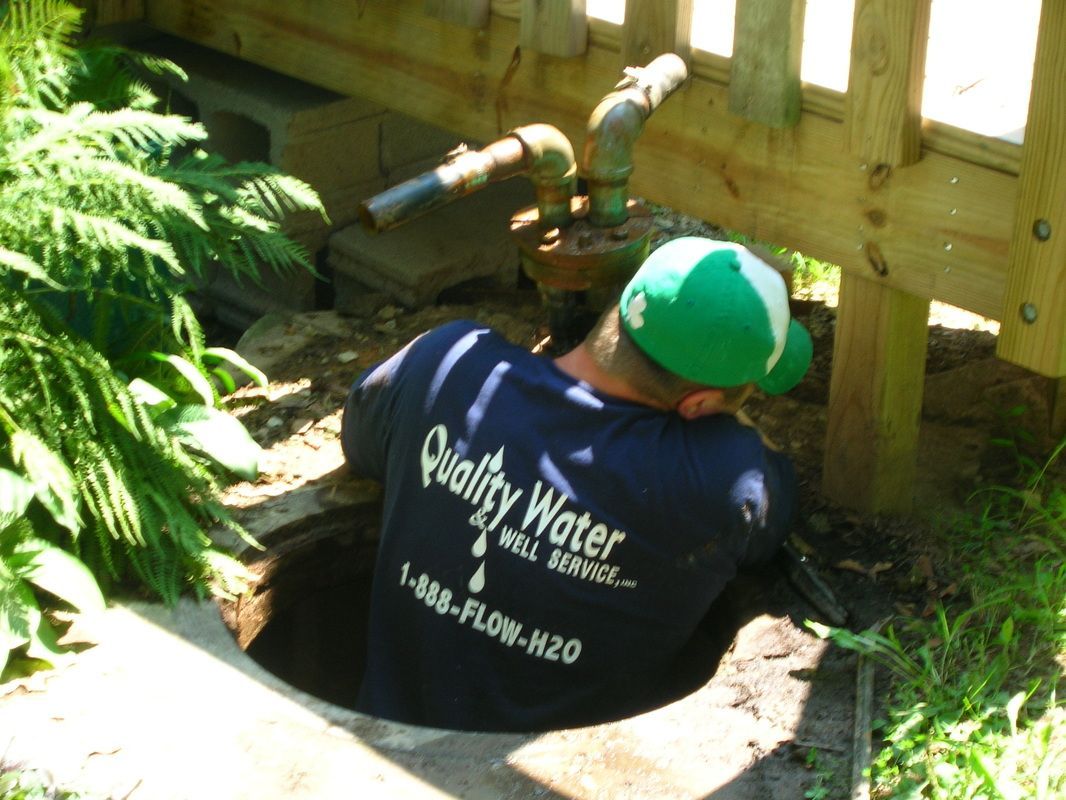 Worker in green cap installing plumbing by a wooden deck in a garden area