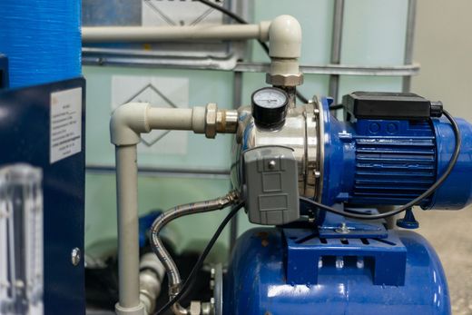 Blue industrial water pump and motor with white piping in a utility room