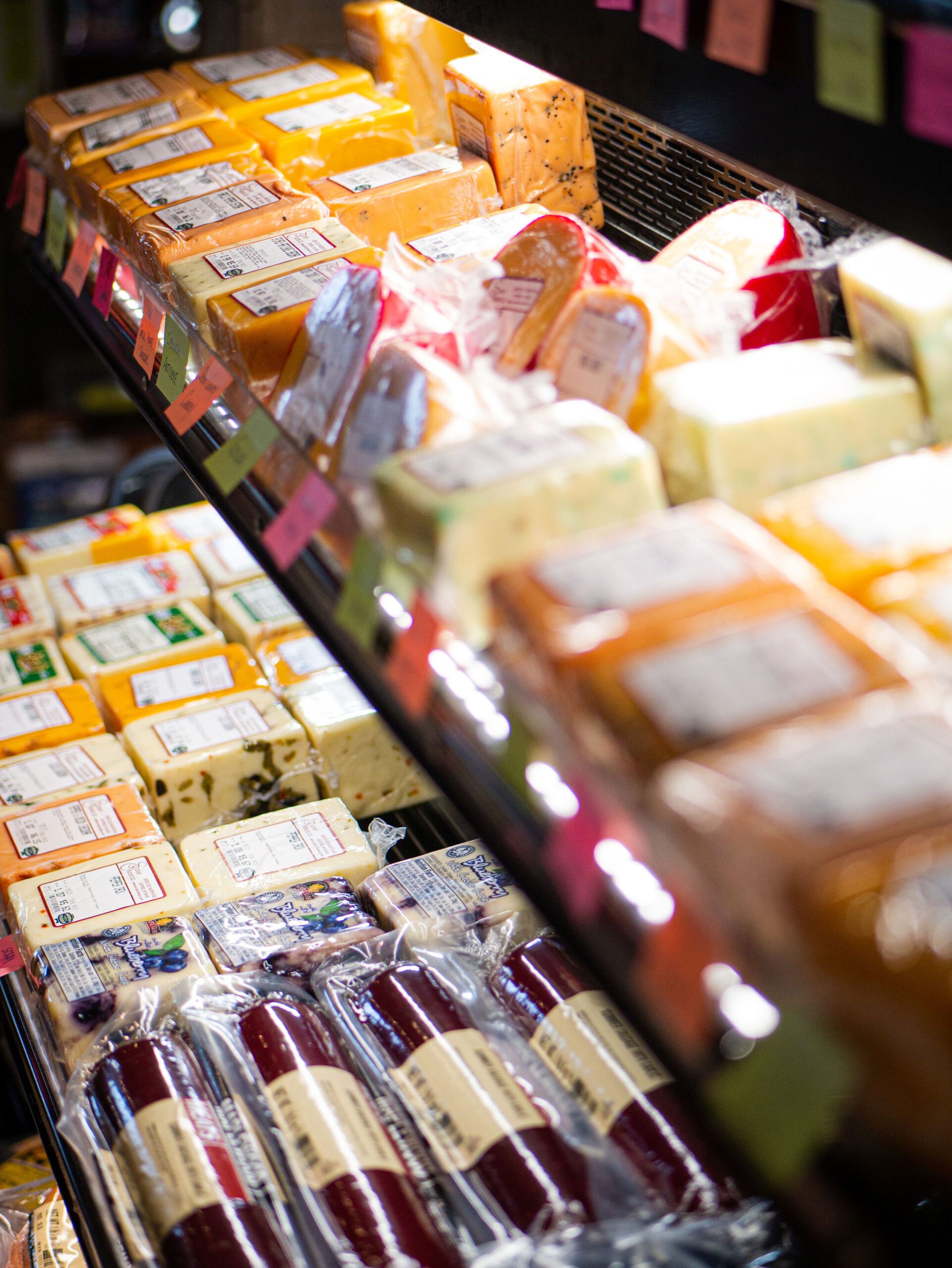 Assorted packaged foods displayed in a refrigerated deli case with labels and colorful wrappers