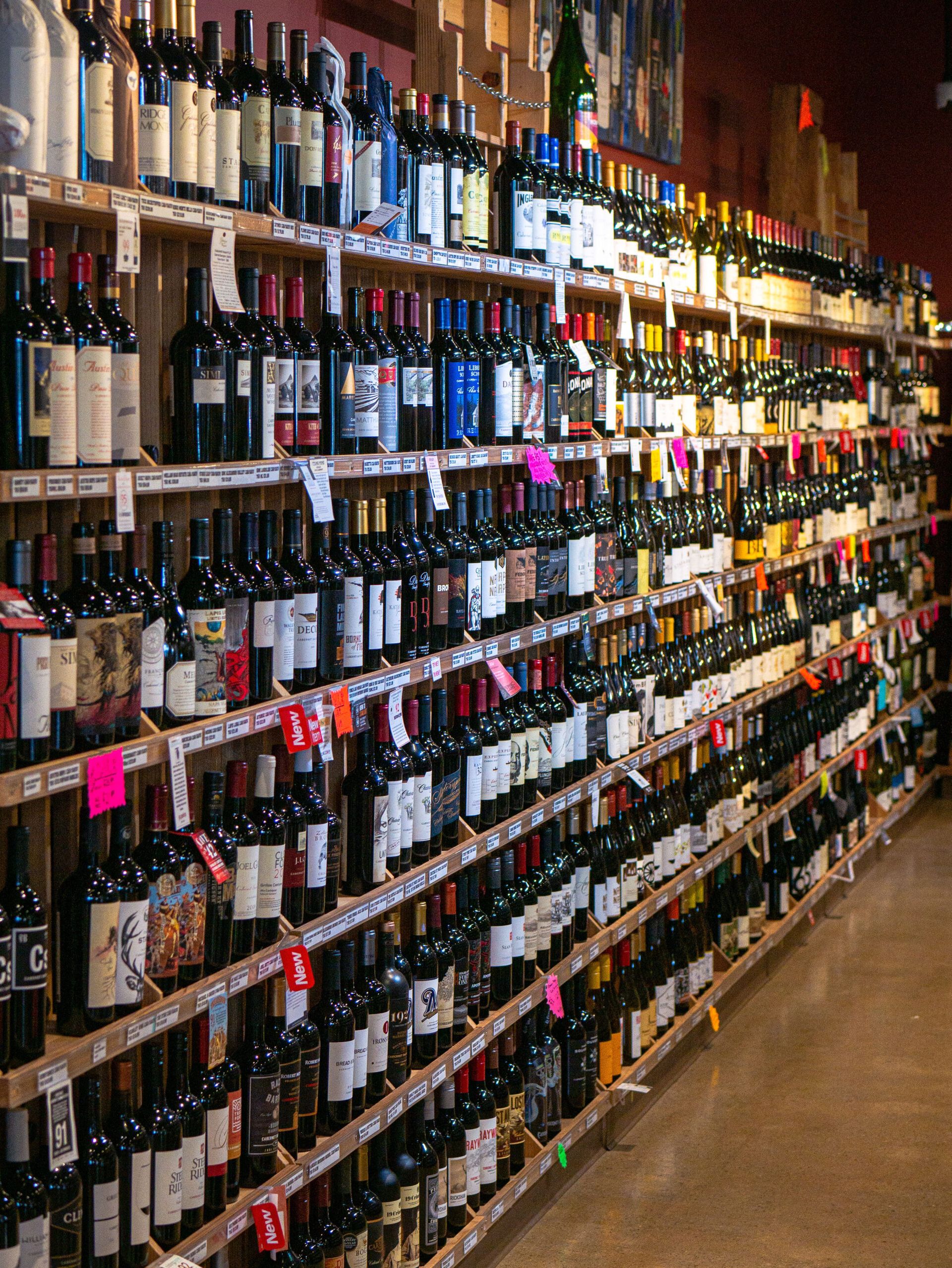 Rows of wine bottles on shelves in a store aisle with price tags