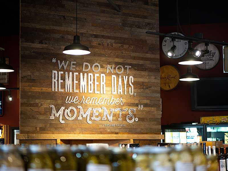 Rustic wall sign reads, “We do not remember days, we remember moments,” in a restaurant or bar.