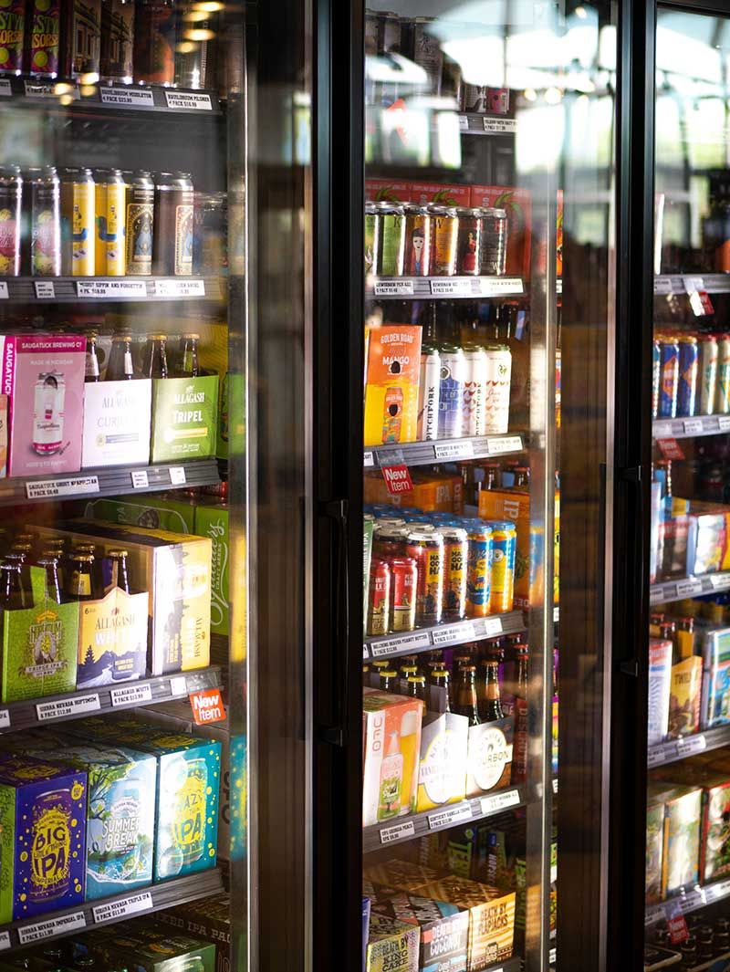 Glass-door convenience store refrigerators stocked with drinks and snacks