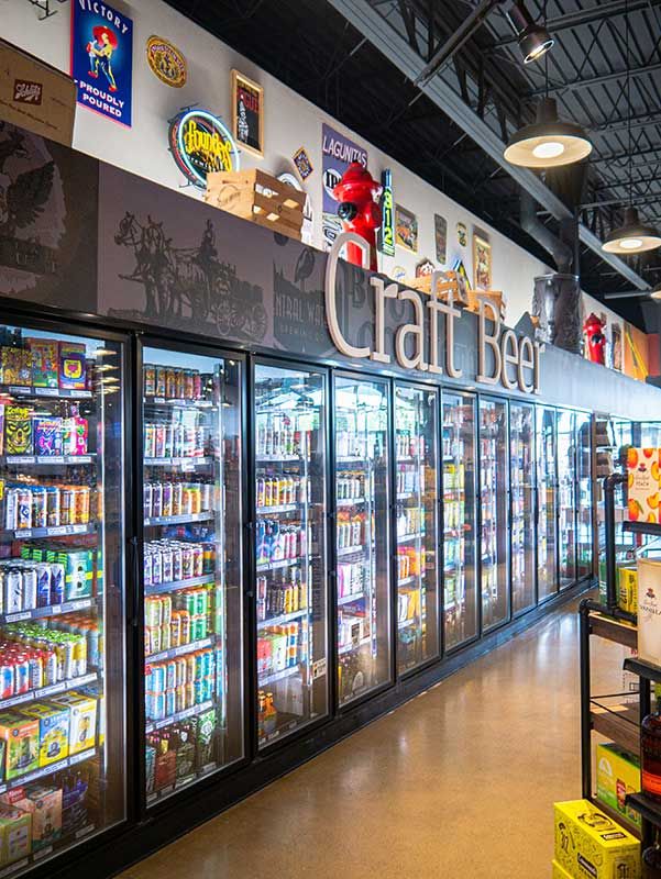 Convenience store beer aisle with glass-door coolers and a large Craft Beer sign