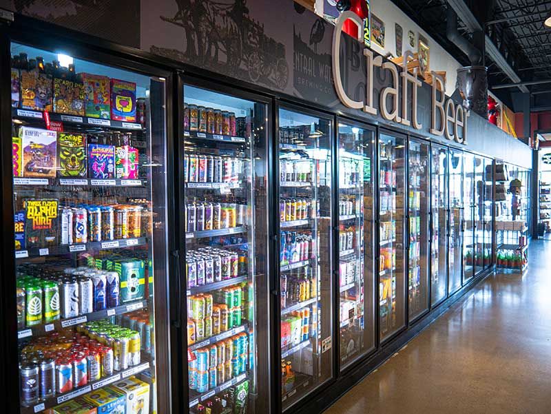 Refrigerated beverage coolers lined with drinks in a convenience store aisle