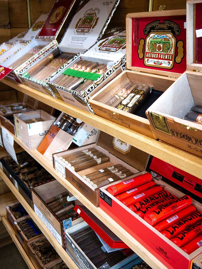 Wooden shelves stocked with assorted cigars in colorful boxes and wrappers