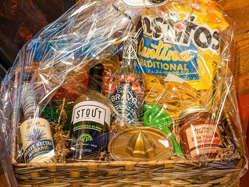 Gift basket with assorted gourmet snacks and beers in a wicker basket wrapped in clear cellophane