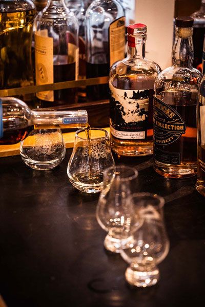 Whiskey bottles and tasting glasses arranged on a bar counter with warm amber lighting