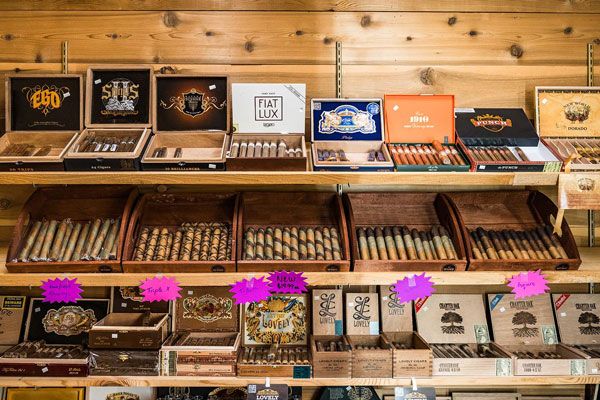 Wooden cigar shop display with neatly arranged cigar boxes and shelves of loose cigars