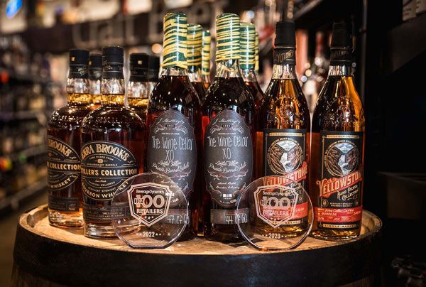 Assorted whiskey bottles on a wooden tray in a dimly lit bar display
