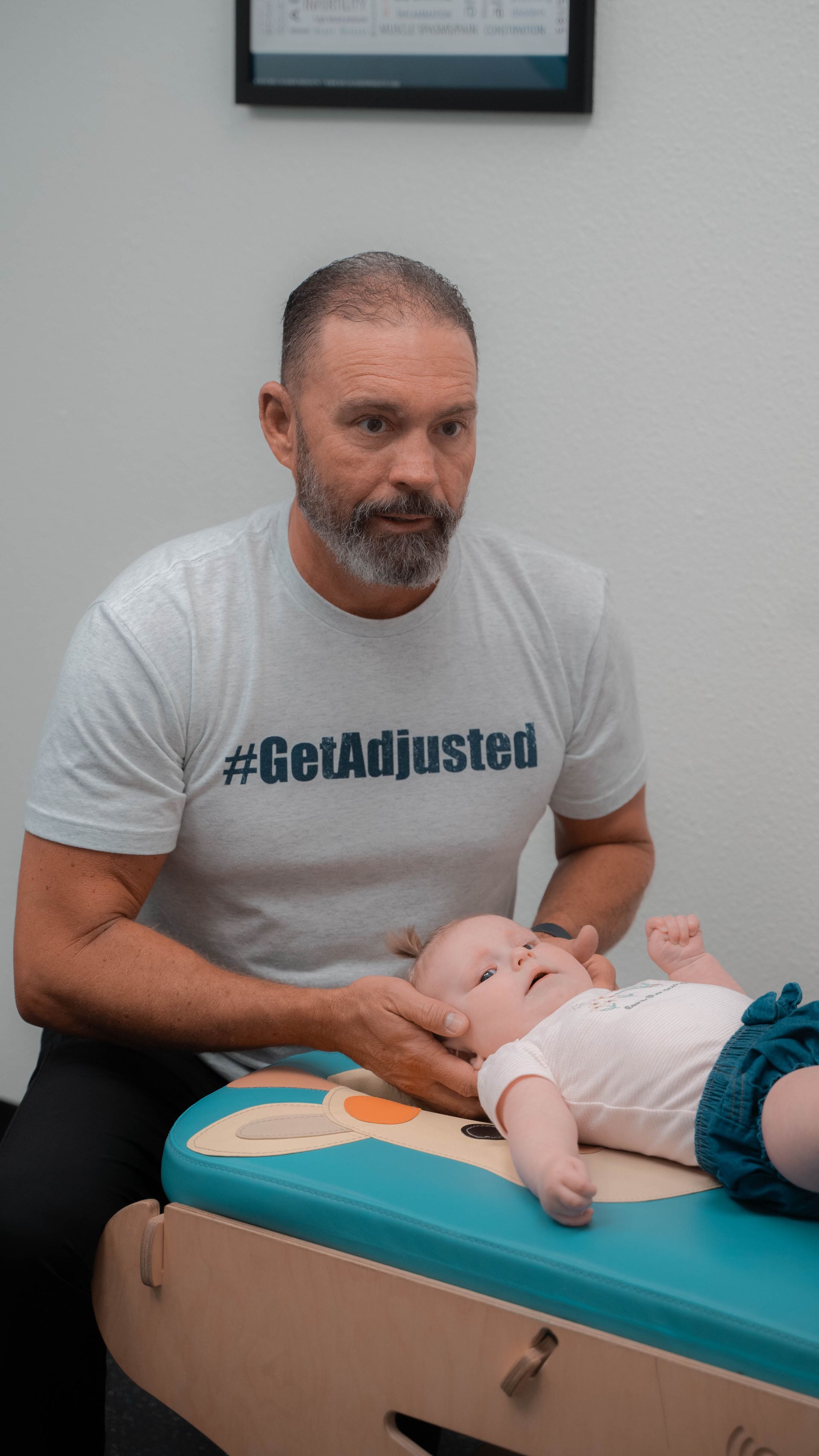 A man is holding a baby on a table.