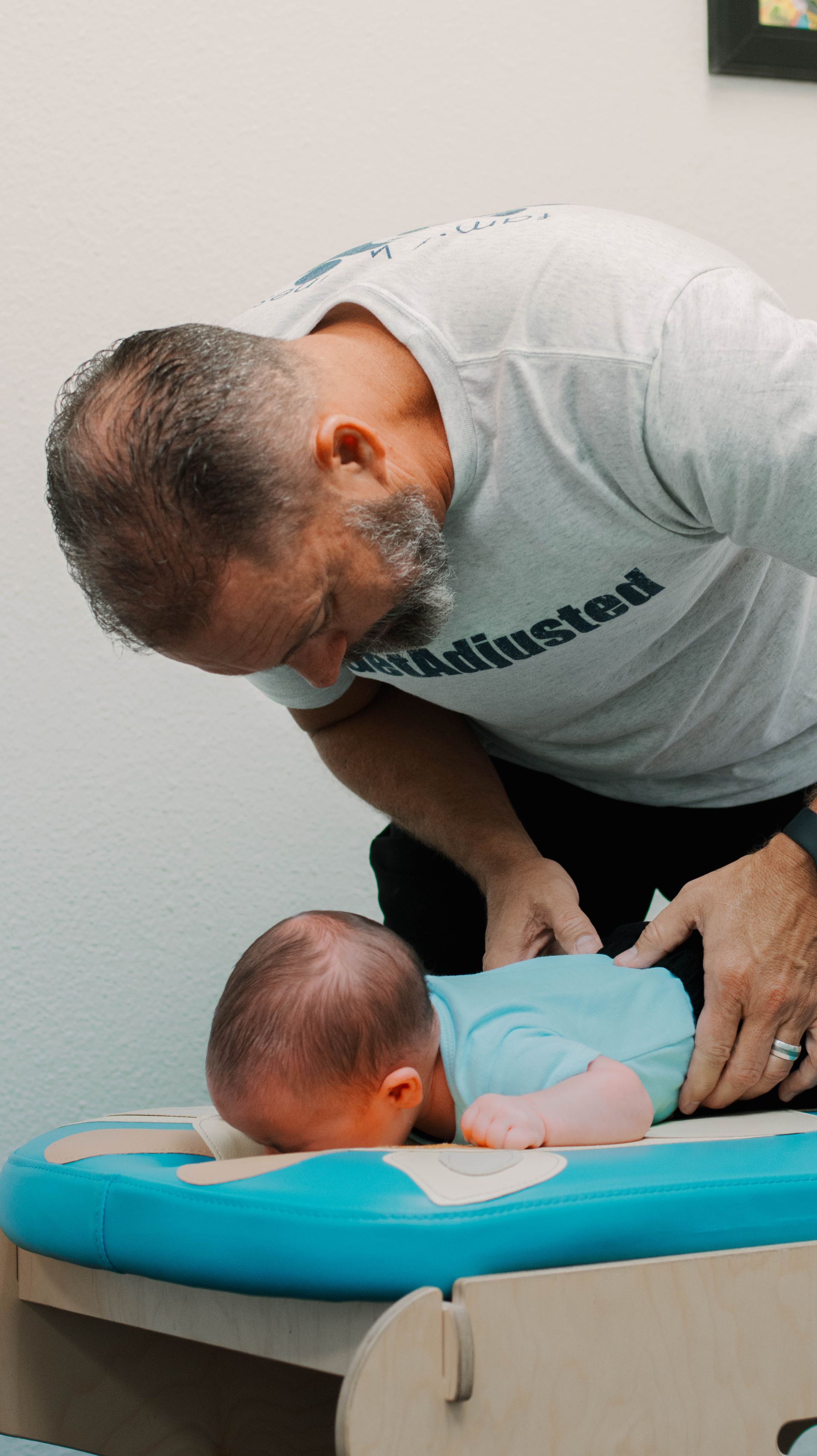 A man is changing a baby 's diaper on a changing table.
