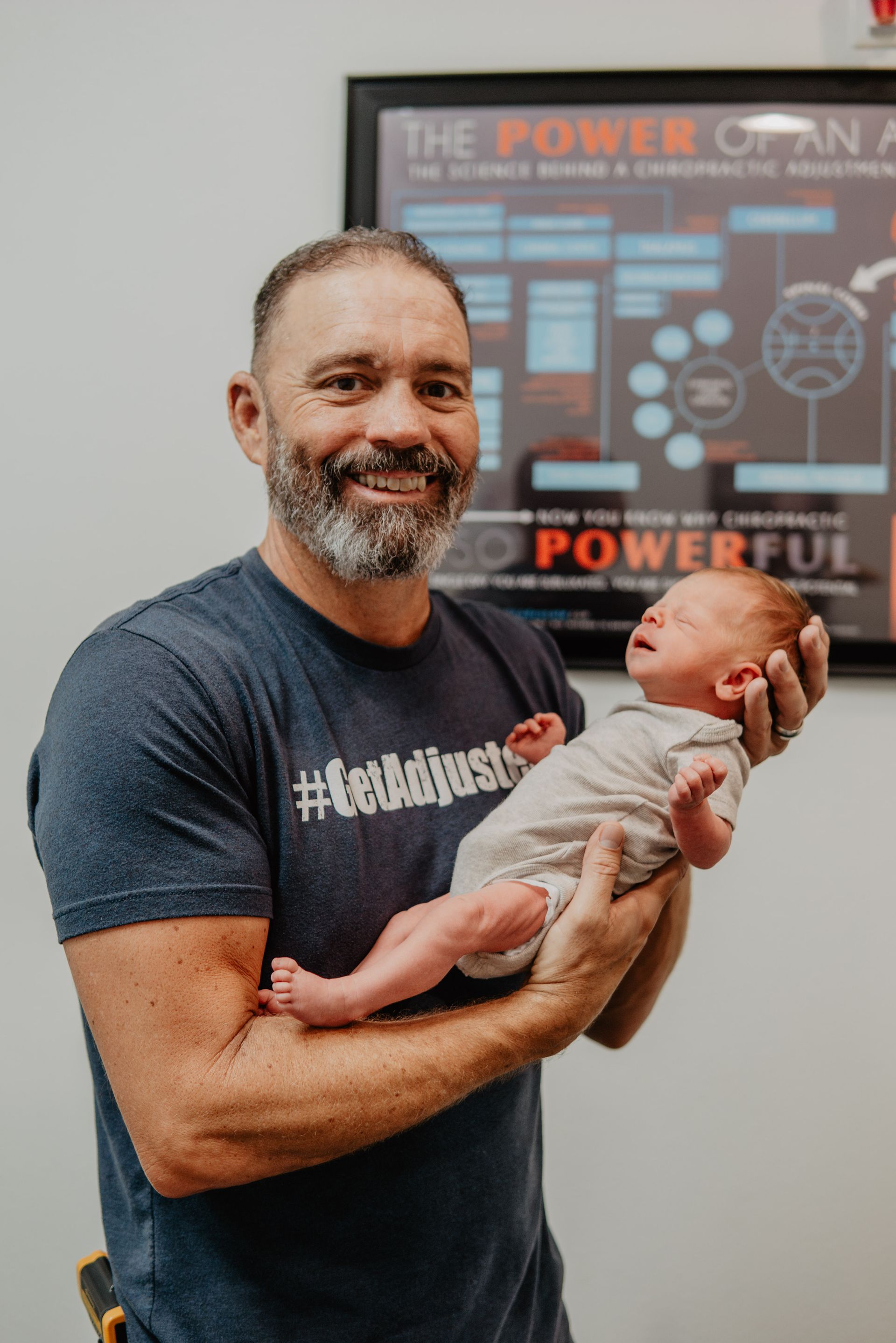 A man in a blue shirt is holding a baby in his arms.