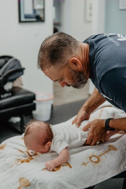 A man is playing with a baby on a table.