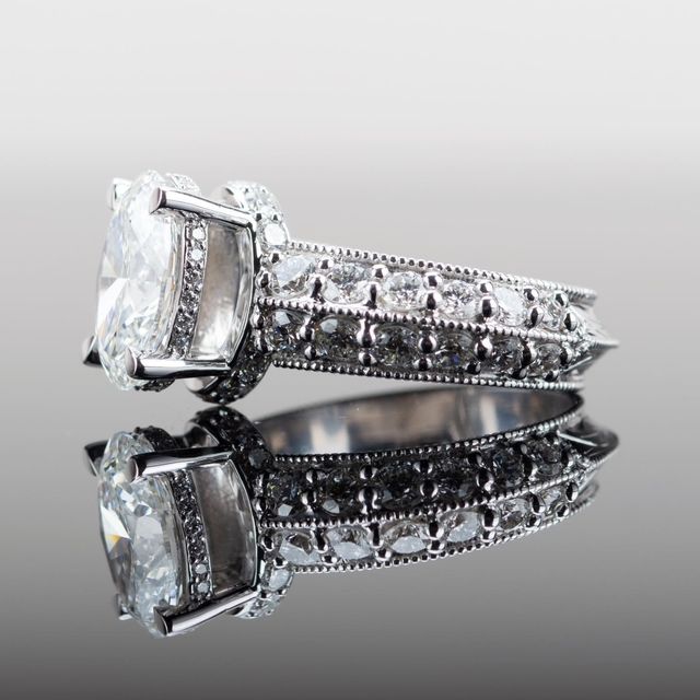 Silver diamond engagement ring with a large clear gemstone on a reflective surface