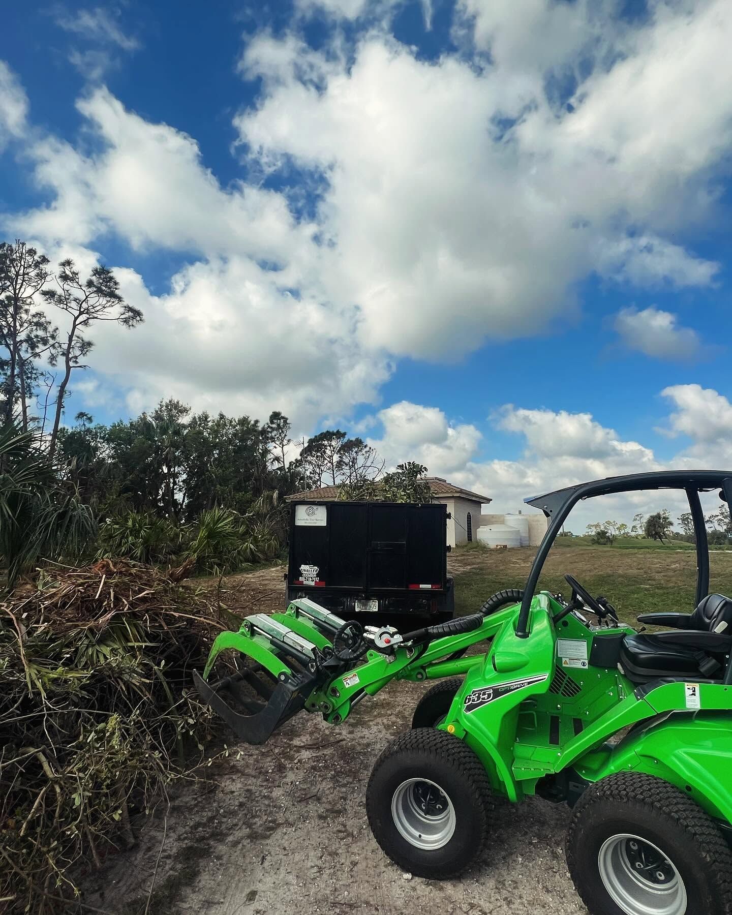 Two bright green ATVs on a muddy trail under a cloudy blue sky.