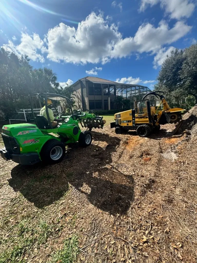 Green and yellow forklifts on a gravel lot outside a building under a bright cloudy sky