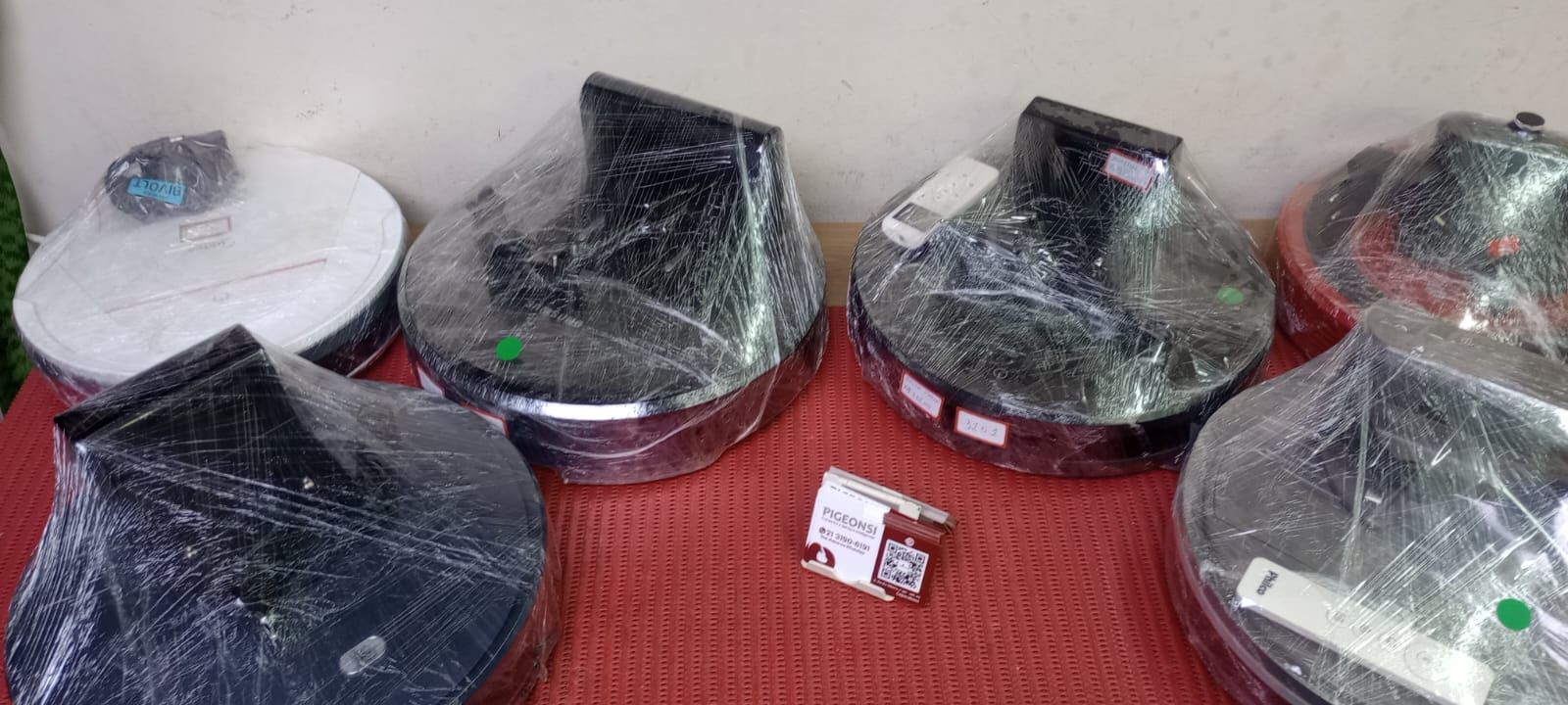 Vários computadores embrulhados em plástico estão sobre uma mesa.