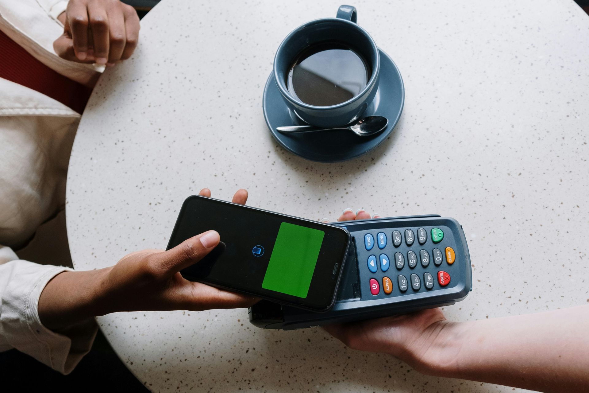 Uma pessoa está pagando por uma xícara de café com um celular.