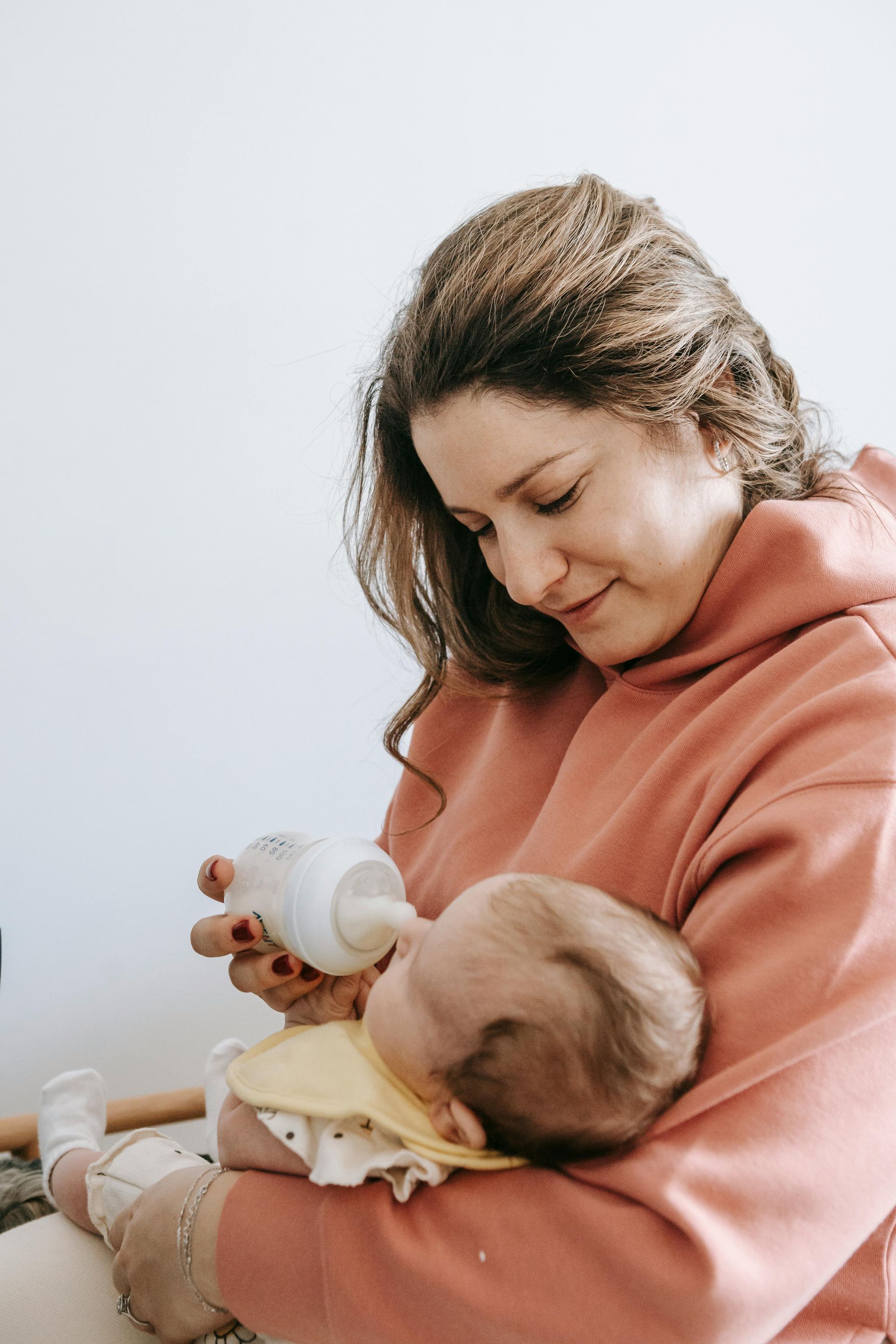 Uma mulher está alimentando seu bebê com mamadeira.