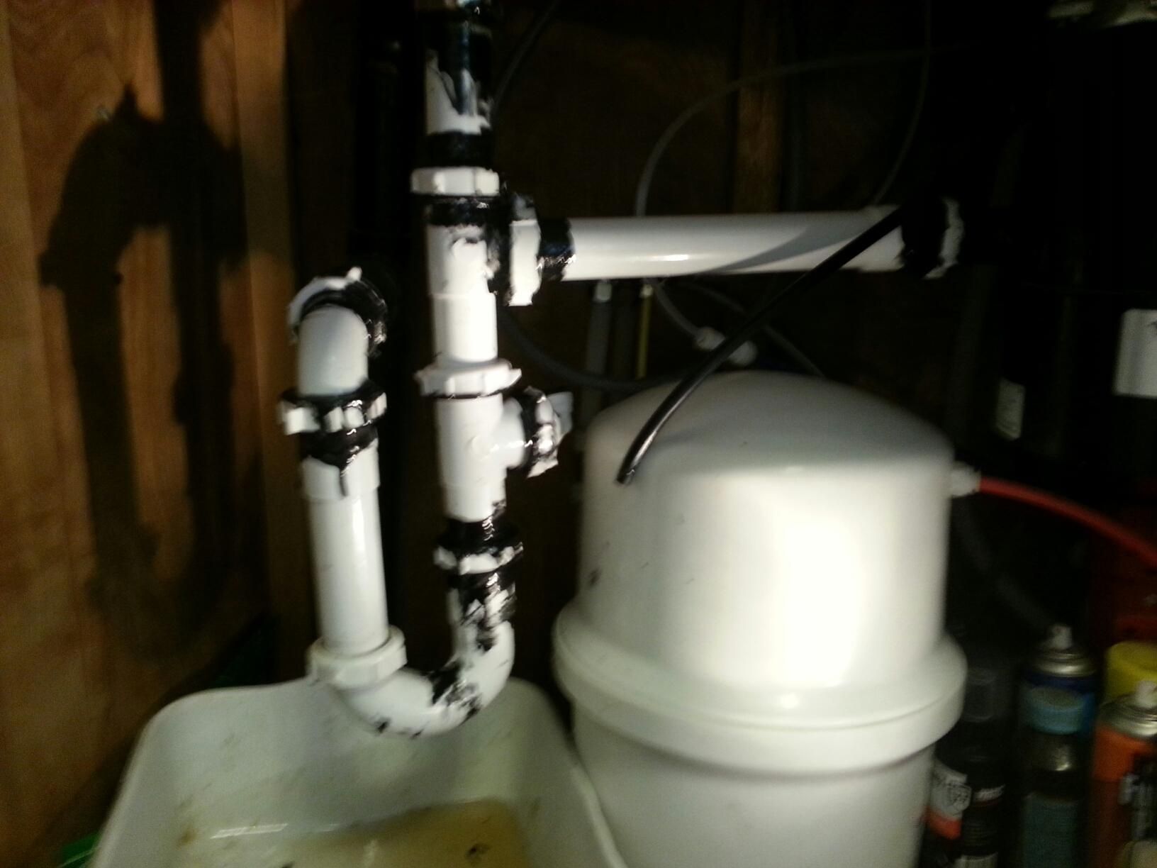 White water heater with exposed plumbing pipes in a dim utility room