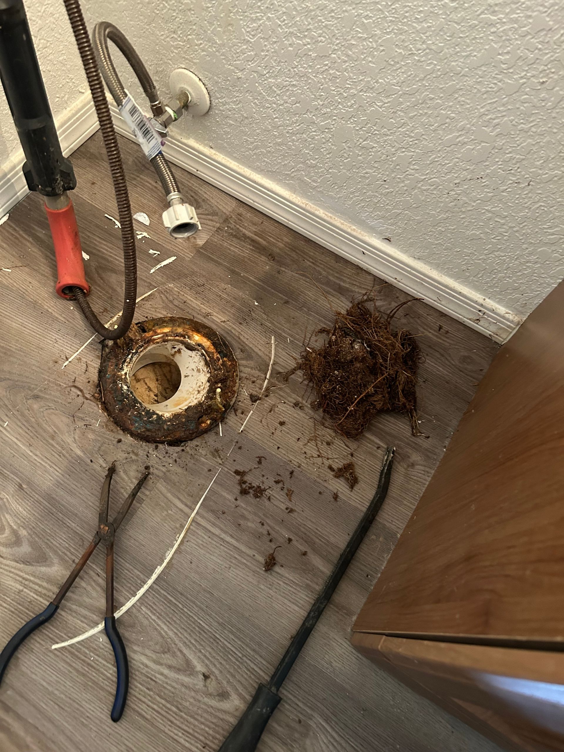Debris and rust around a floor drain in a utility room, with tools and cables nearby. Debris and rust around a floor drain in a utility room, with tools and cables nearby.