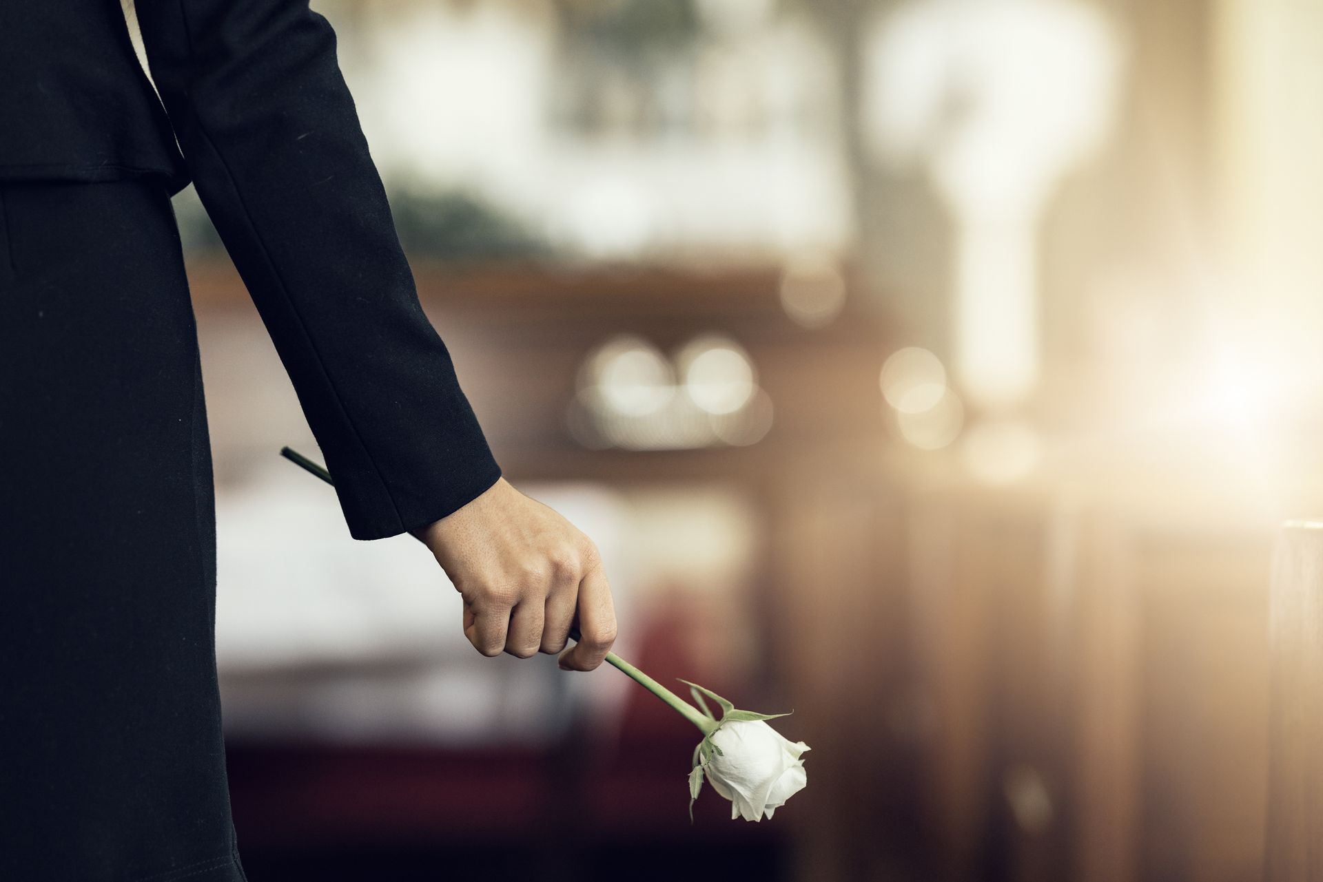 Mourners carry a wooden casket with white flowers at a funeral procession