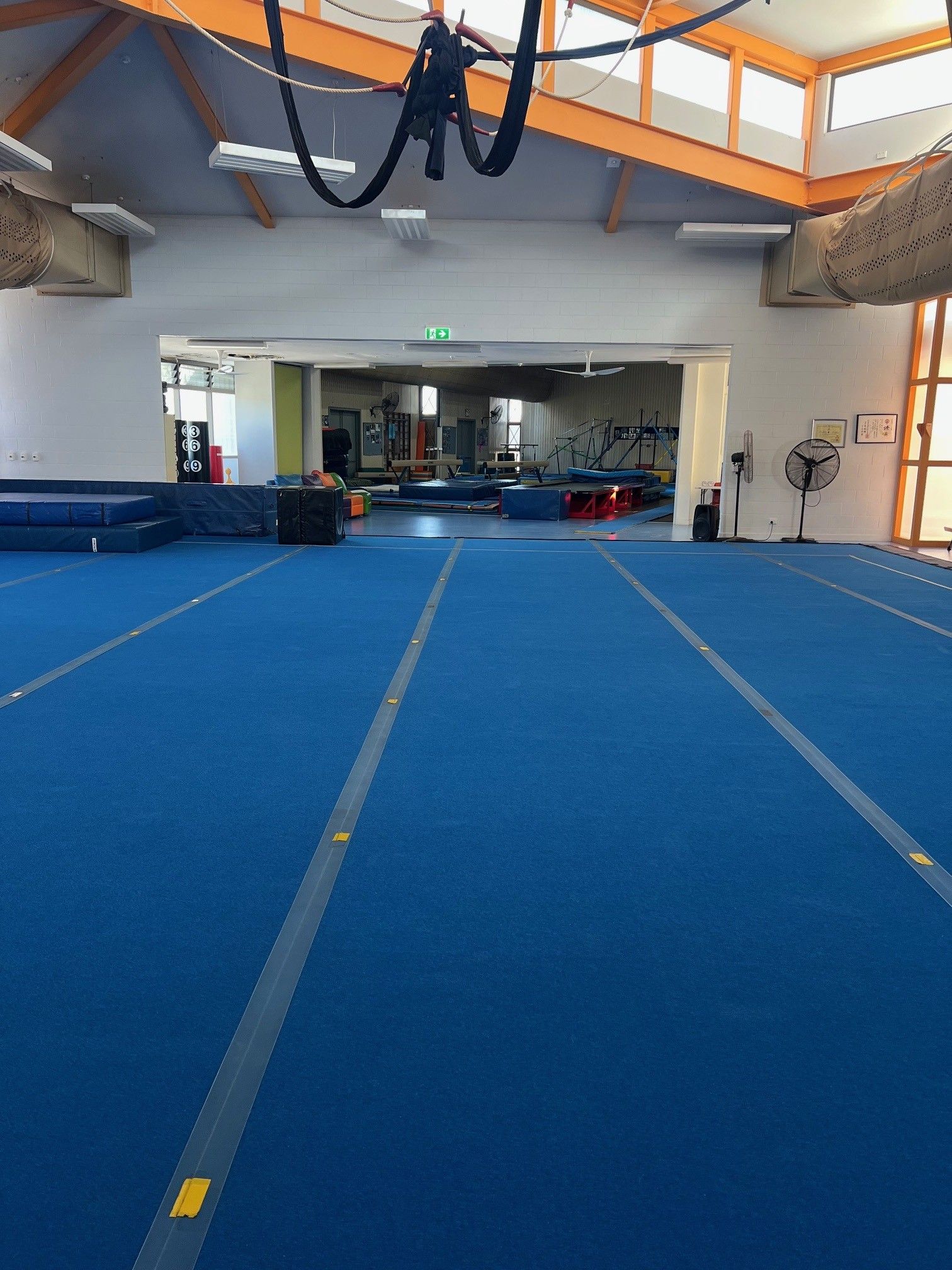 Blue floor in an indoor gym with equipment and a doorway to another area.