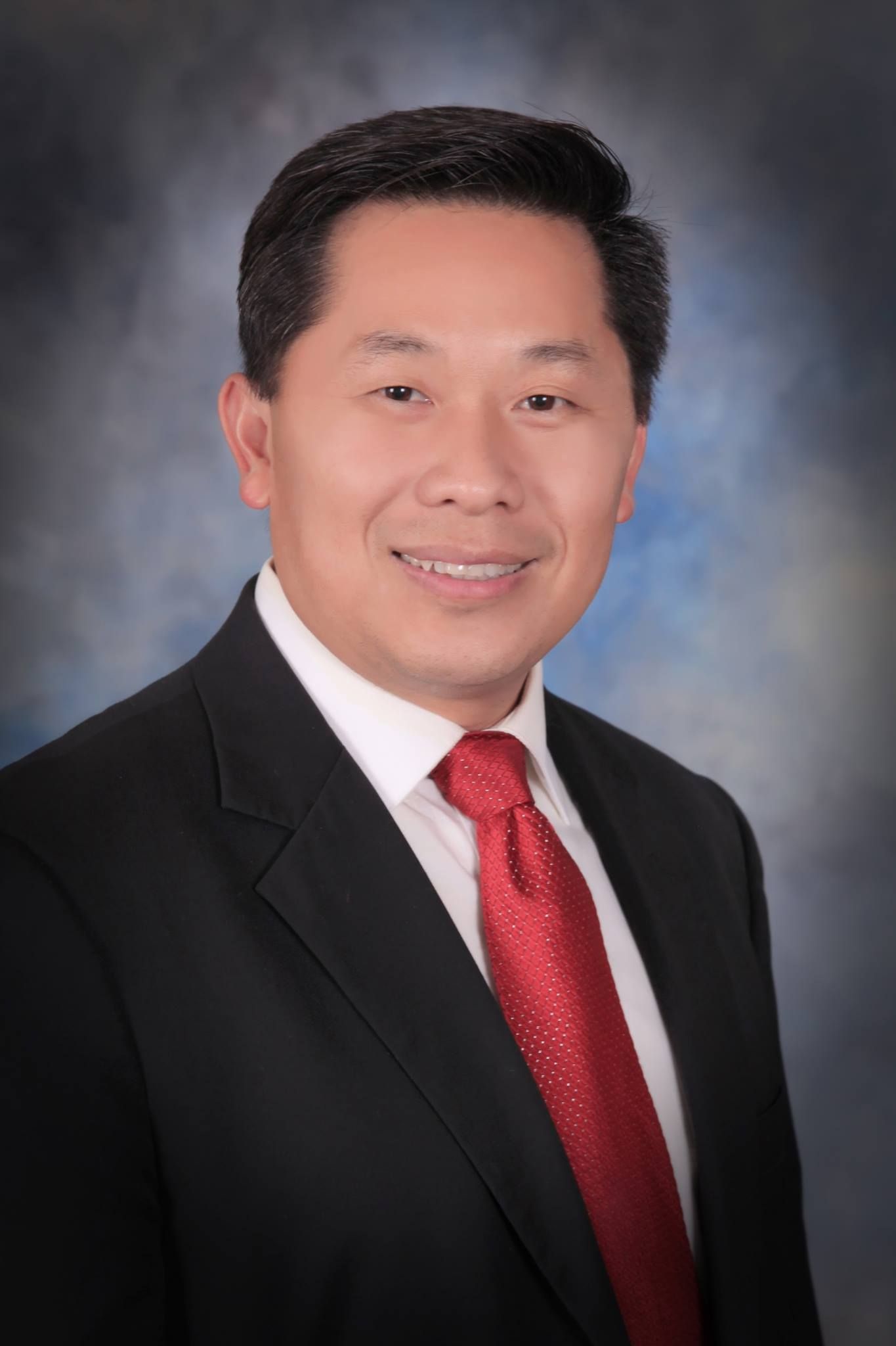 A man in a suit and tie is smiling for the camera