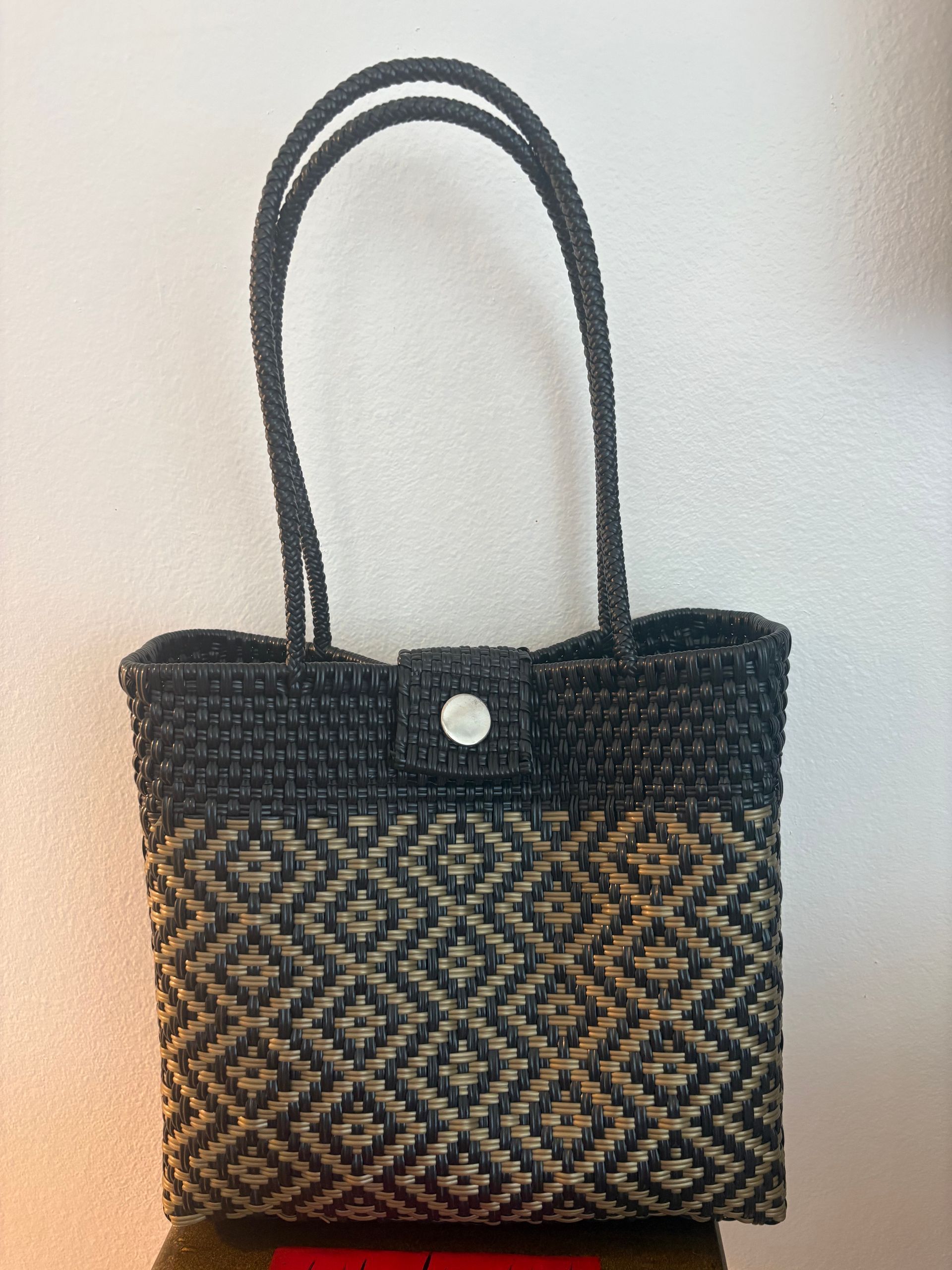 Black-and-tan woven tote bag with long handles on a plain light background
