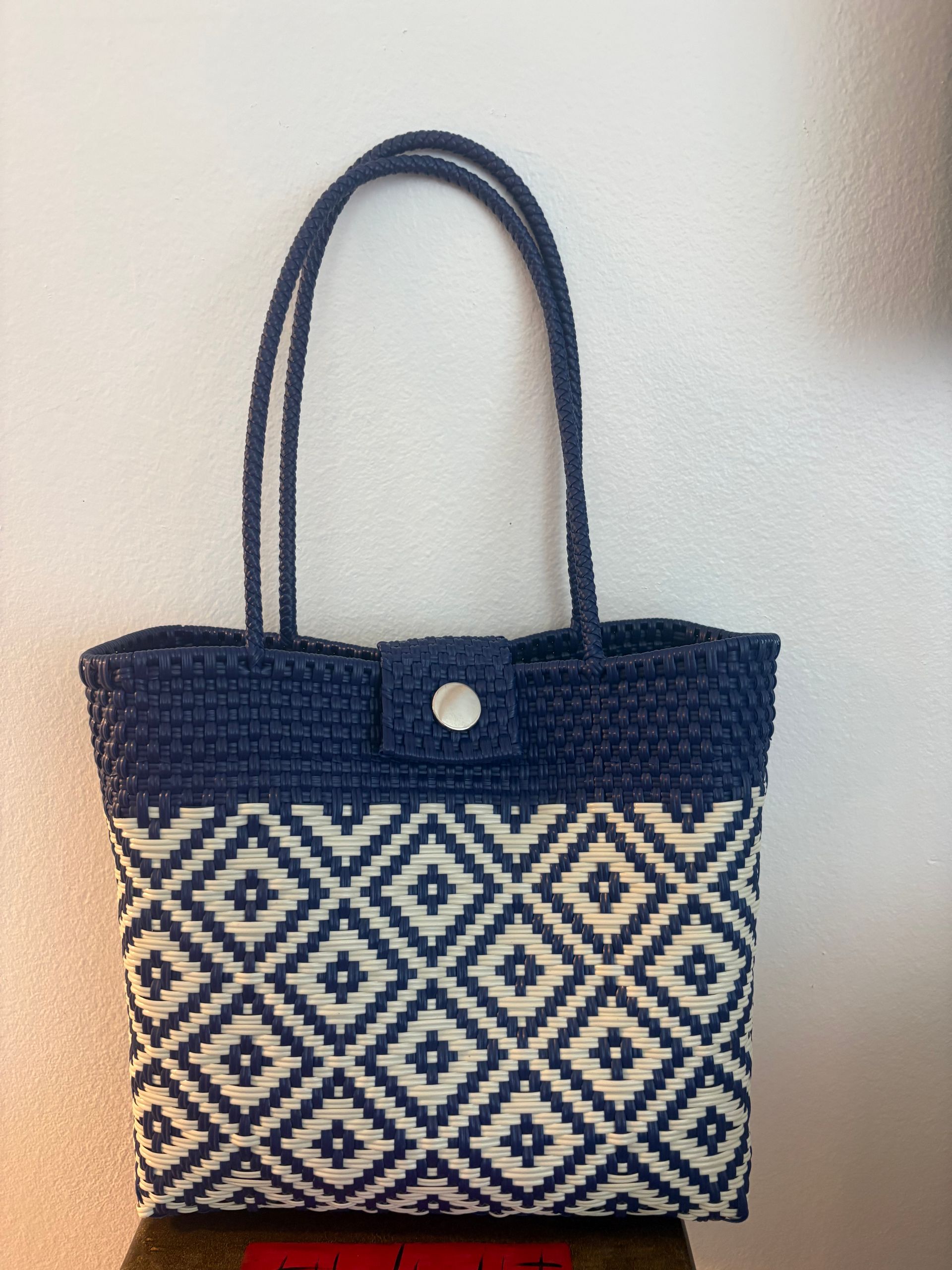 Blue-and-cream woven tote bag with diamond pattern and double handles on a plain background