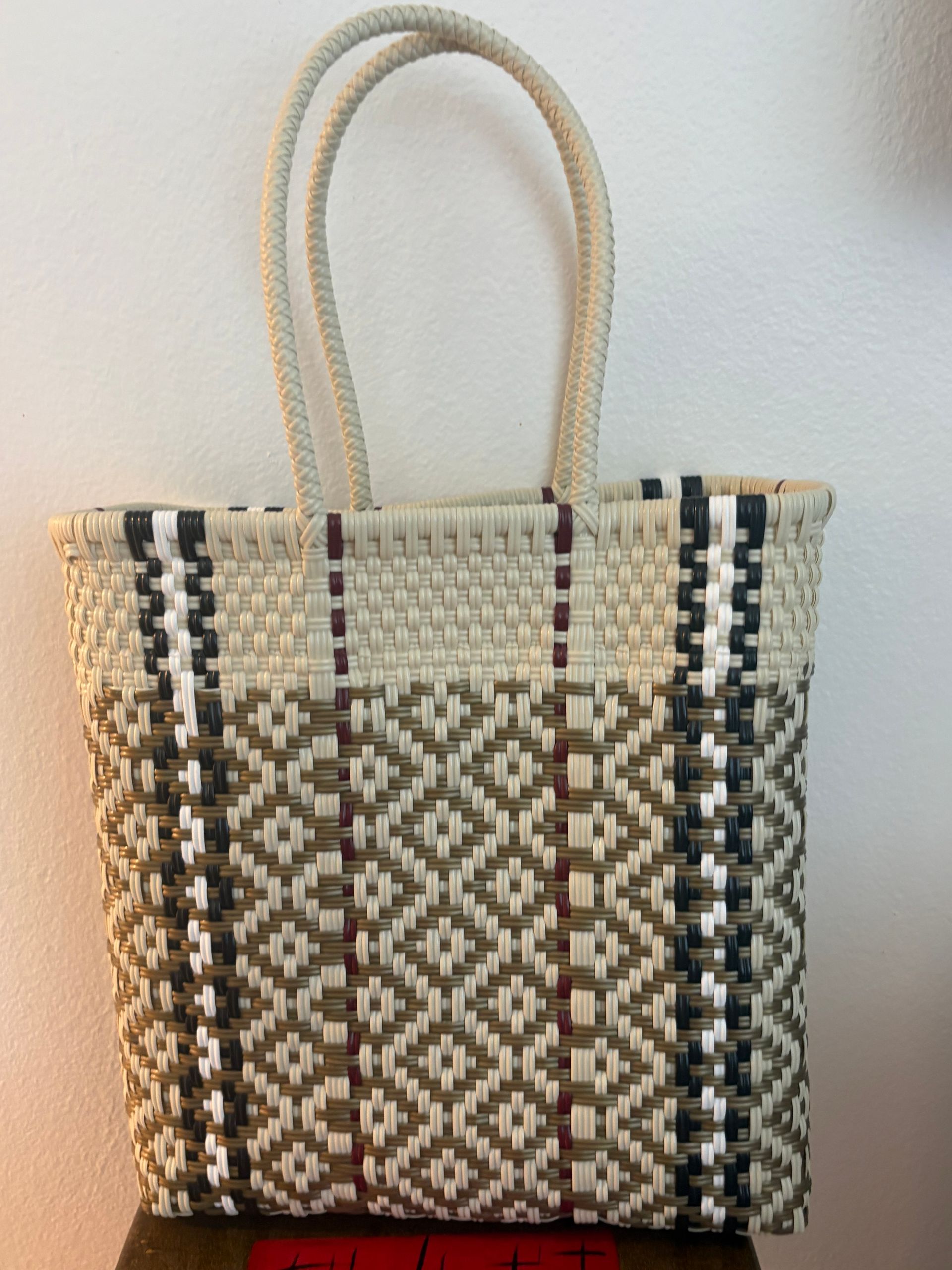 Woven tote bag with beige handles and brown, cream, and black geometric pattern