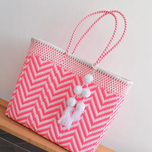 Pink-and-white chevron tote bag with pom-pom tassel on a shelf