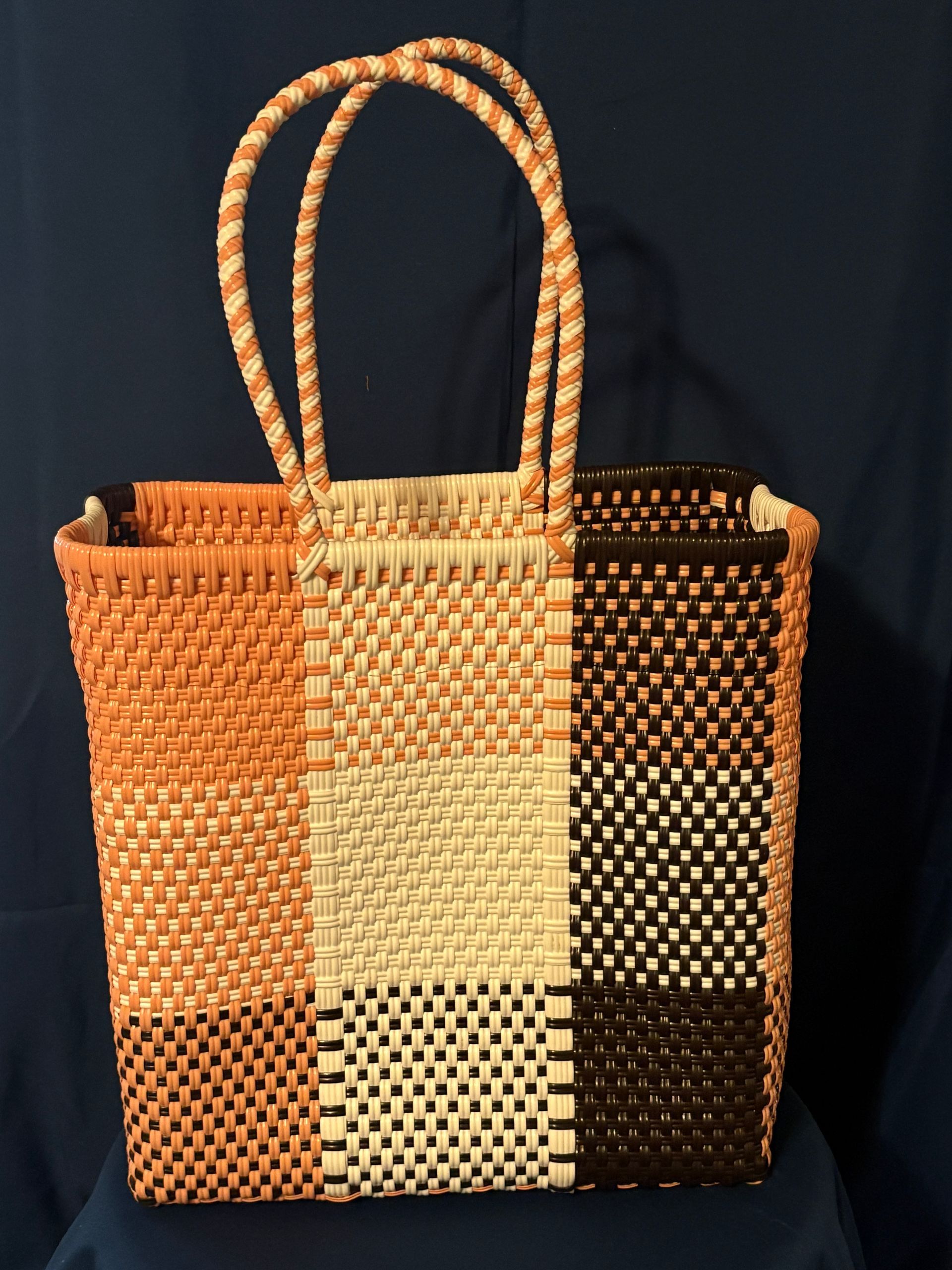 Woven tote bag with striped orange, cream, and brown pattern on a dark background