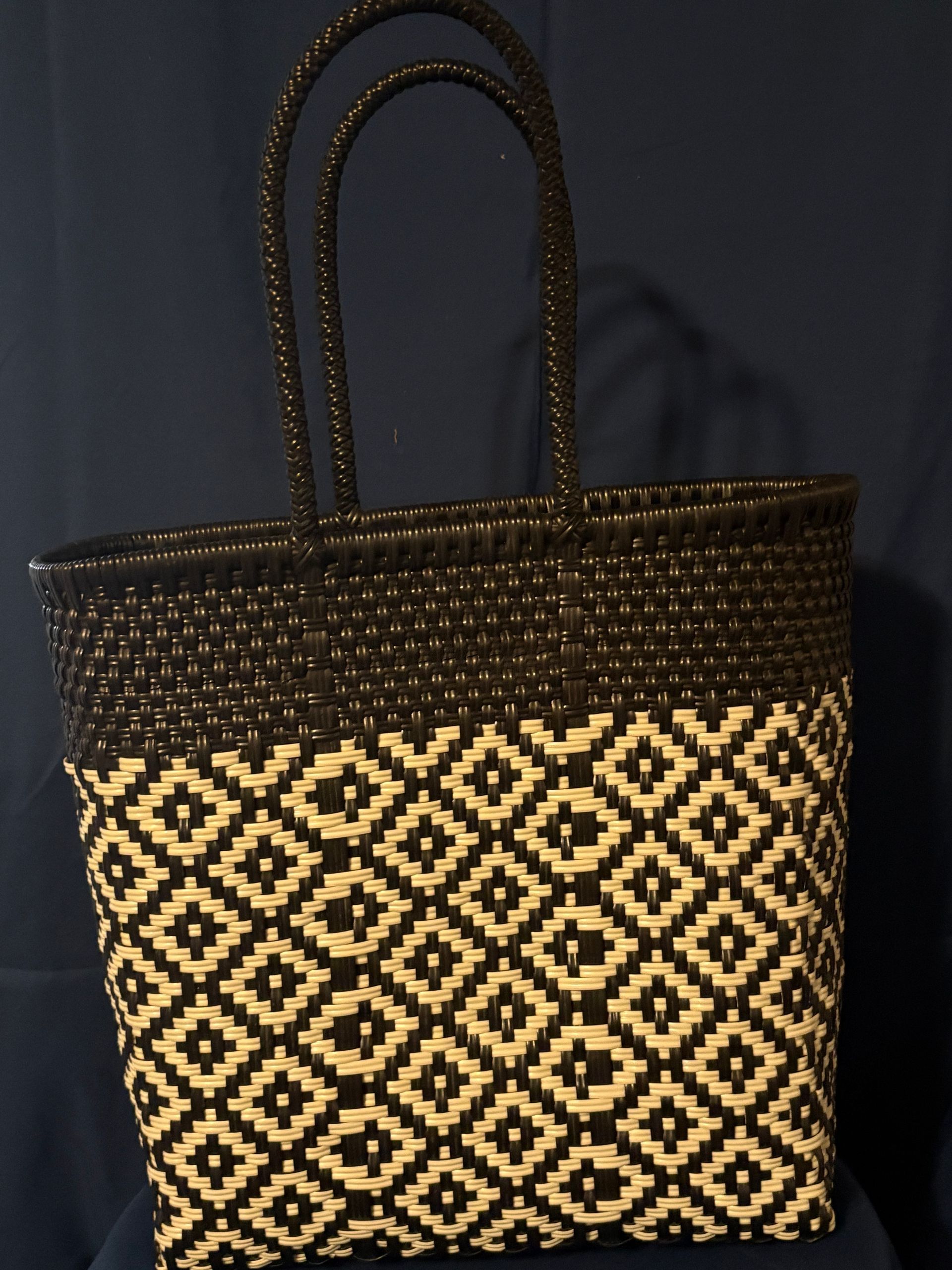 Black woven tote bag with tan geometric pattern on a dark background