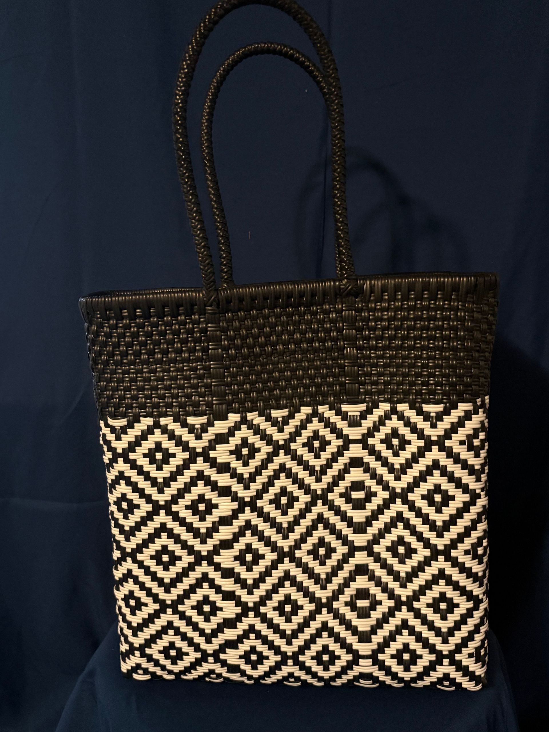 Black woven tote bag with cream geometric pattern on a blue background