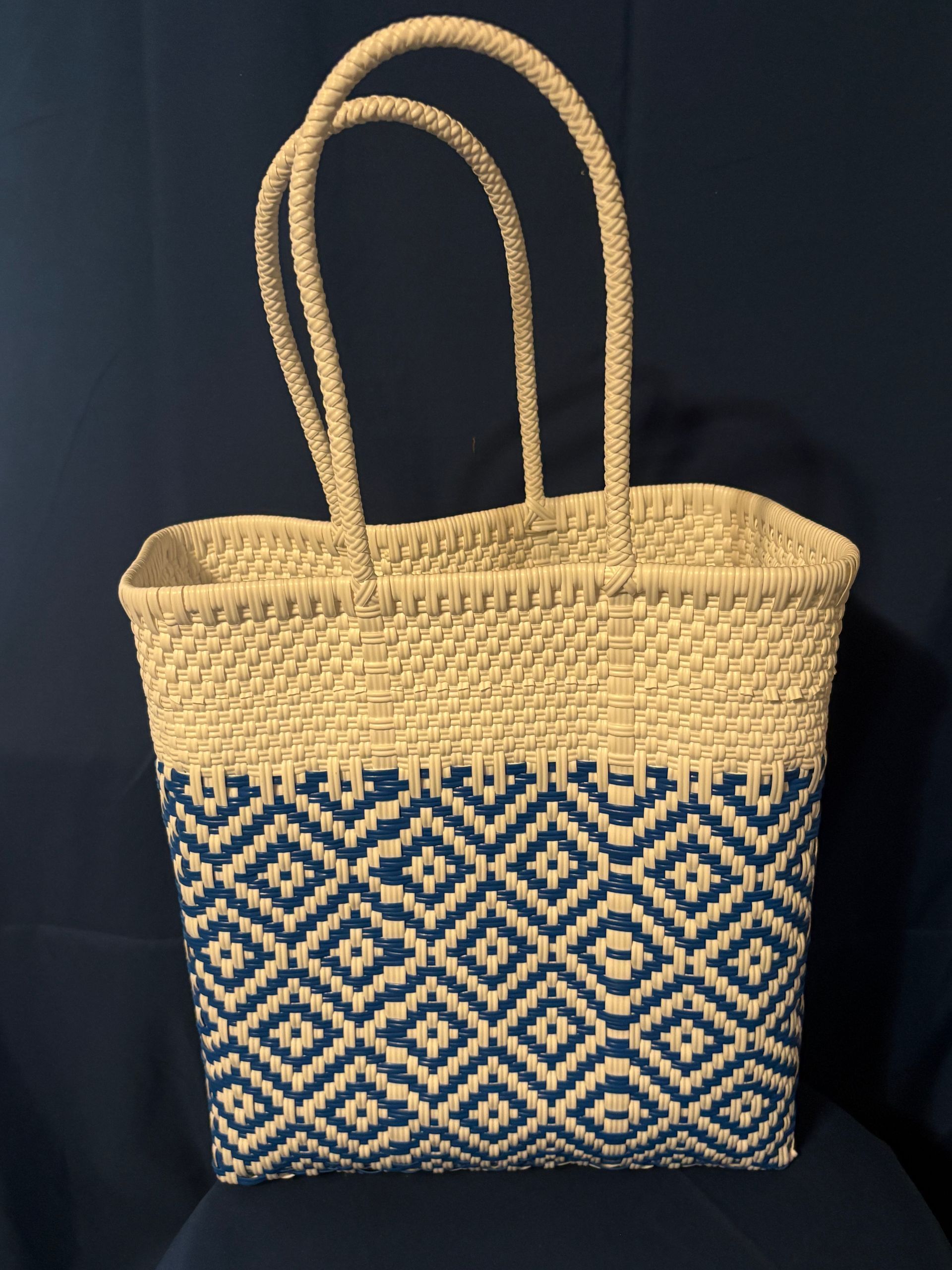 Woven straw tote bag with tan handles and navy geometric pattern