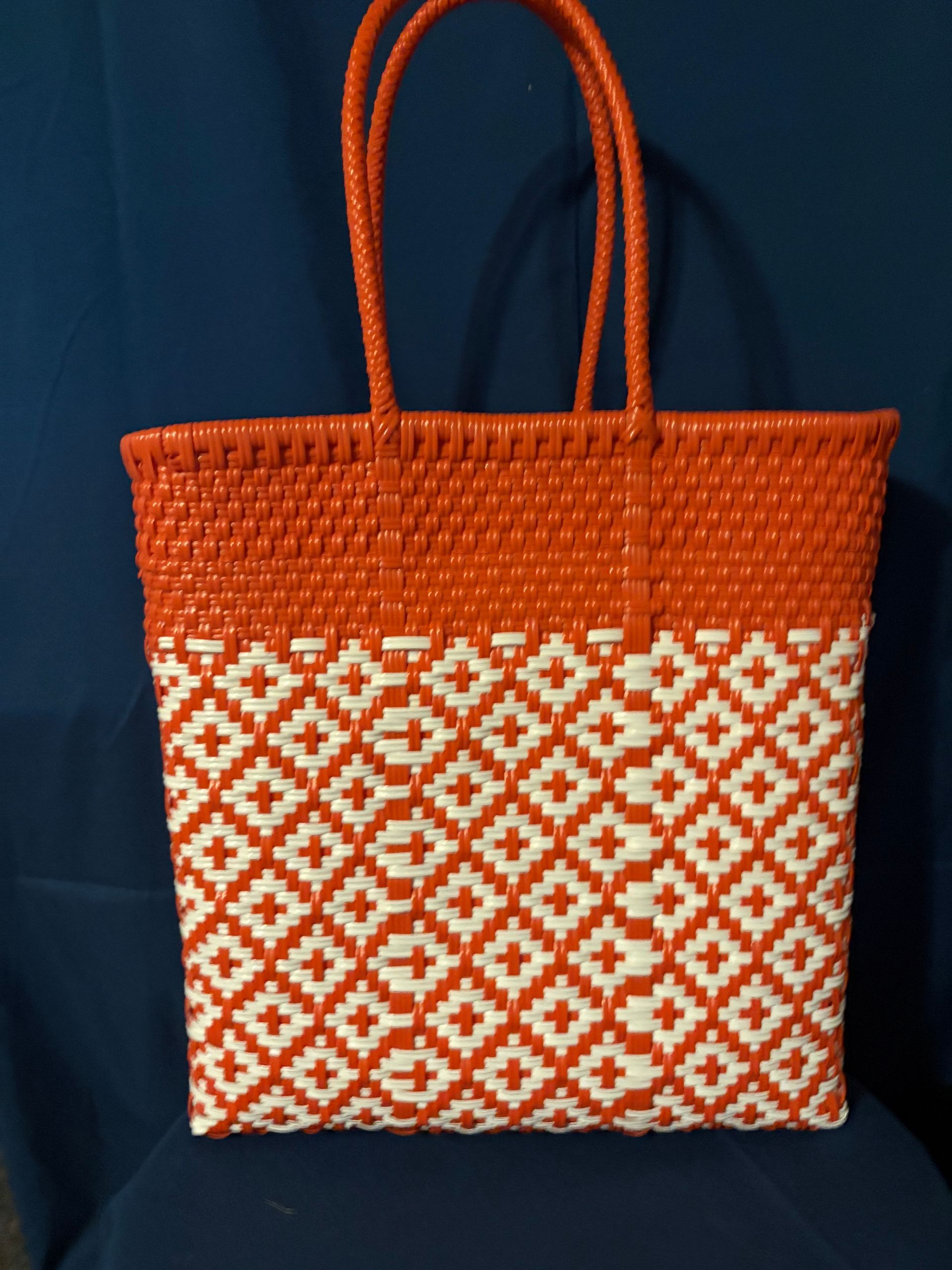 Orange woven tote bag with white geometric pattern on a dark blue background
