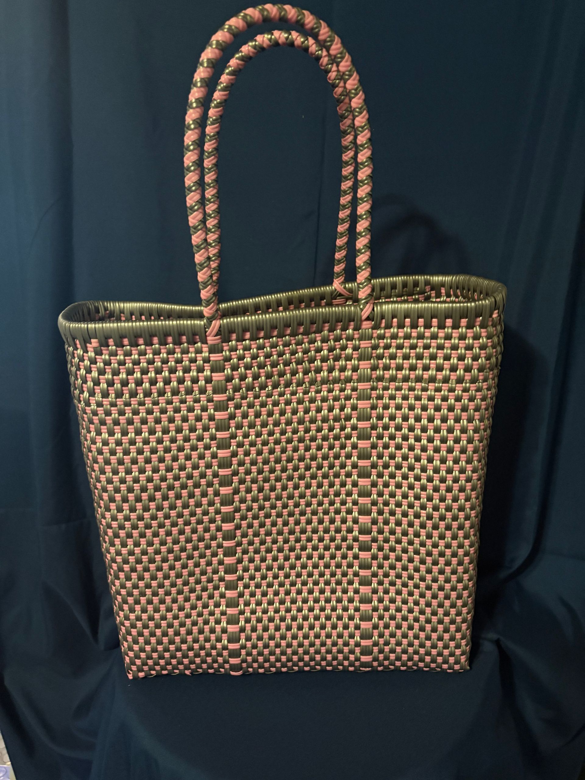 Woven tote bag with braided handles, tan and brown, against a dark blue background