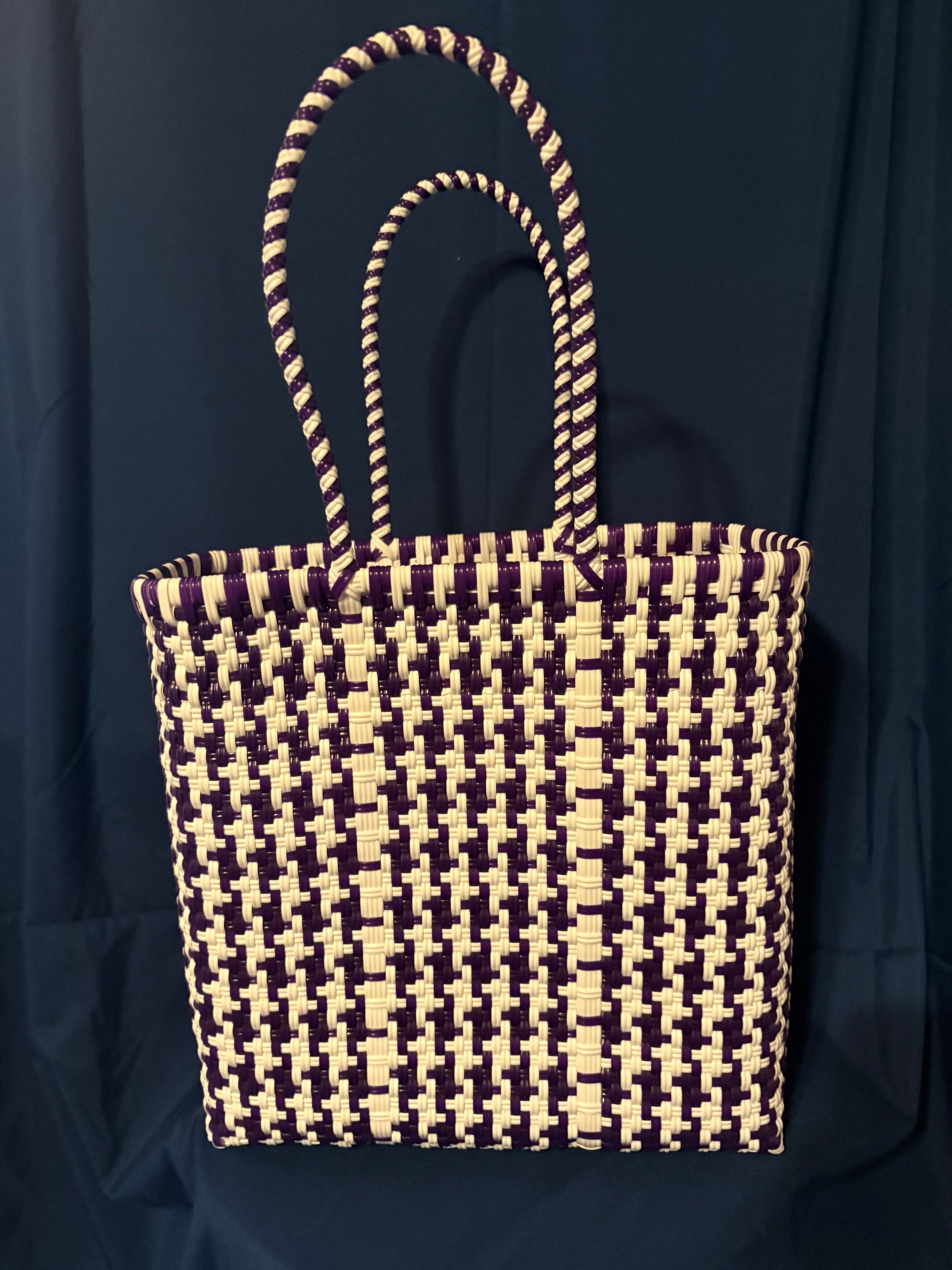 Black-and-white woven tote bag with two handles on a dark background