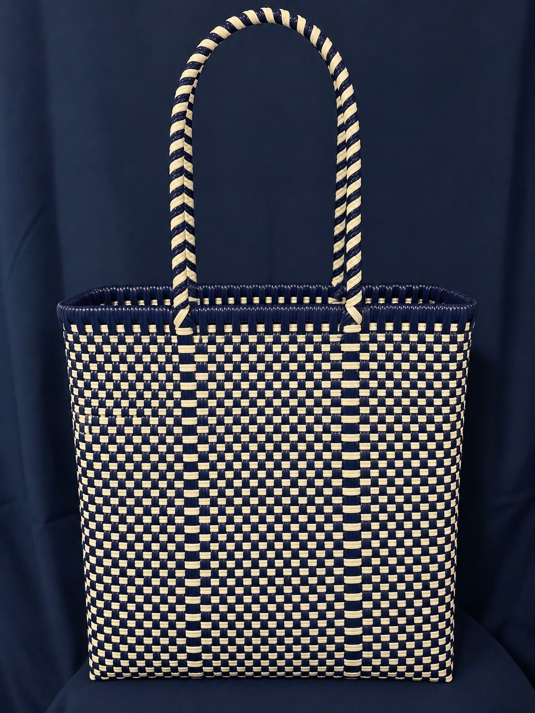 Black tote bag with gold polka dots and braided handles against a dark background