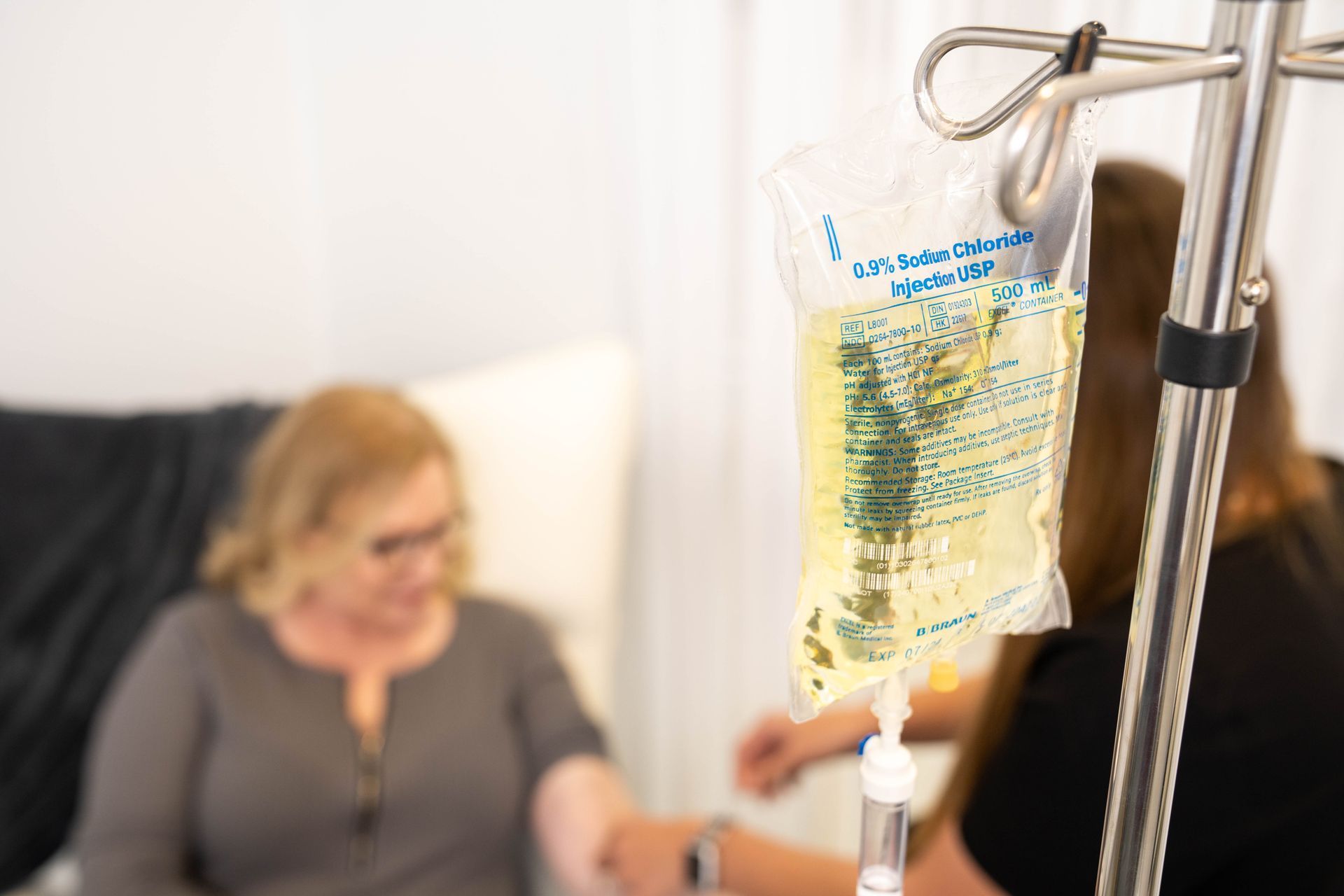 A woman is getting an injection in her arm while another woman looks on.