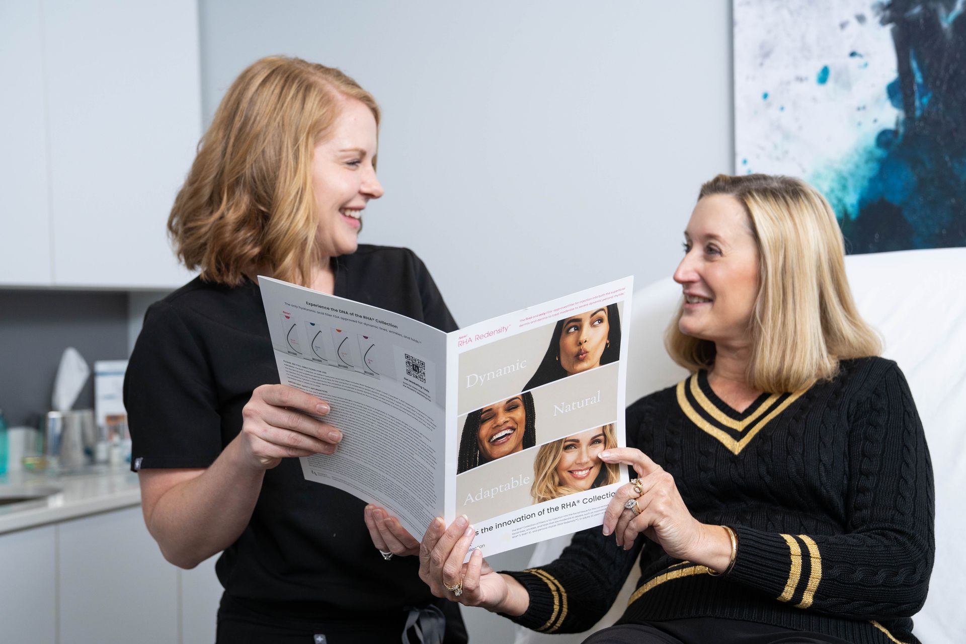 Two women are sitting next to each other looking at a book.
